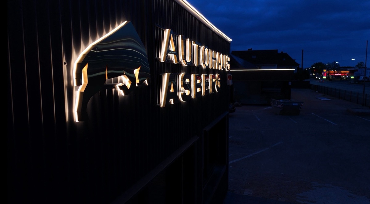 Autohaus Asberg: goldene Rückleuchter-Buchstaben mit Logo