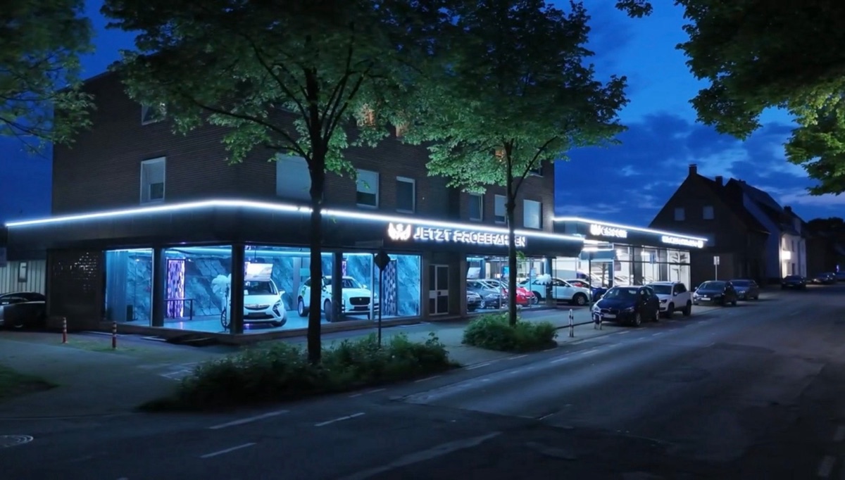 Autohaus bei Nacht mit durchgehender LED-Lichtlinie und Leuchtbuchstaben