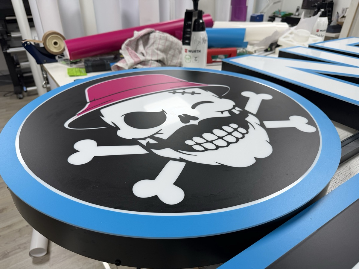 Runder Leuchtkasten mit Totenkopf-Logo in der Werkstatt